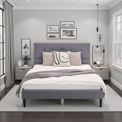 A bedroom scene featuring a gray upholstered bed.