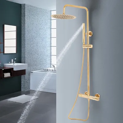 A modern bathroom with a gold shower system in use, showing water spraying.