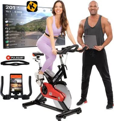 A man and a woman are posing with an indoor cycling bike, a large screen displaying a virtual cycling course, and accessories like a tablet and heart rate monitor.