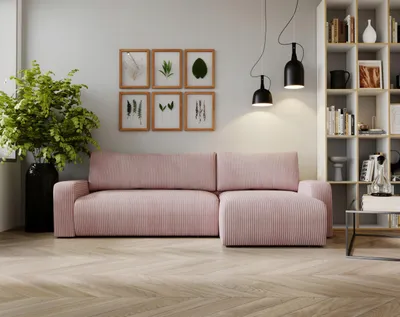 A modern living room with a pink corduroy sectional sofa, a bookshelf, and decorative wall art.