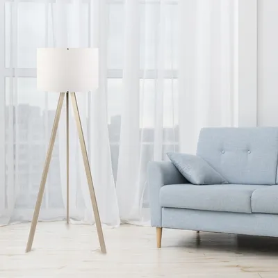 A floor lamp and a sofa are in a room with sheer white curtains in the background.