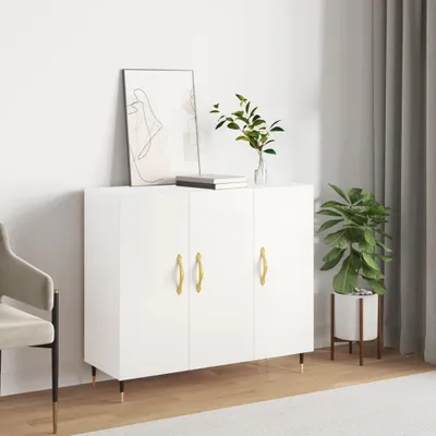 A white sideboard with gold handles is shown in a room with a chair, plant, and curtains.