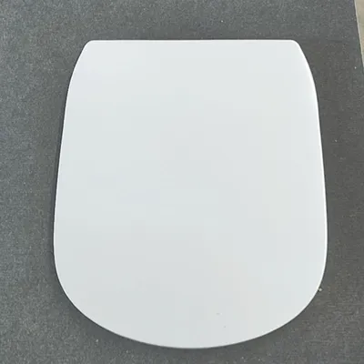 A white toilet seat lid is shown from a top-down perspective on a gray textured surface.