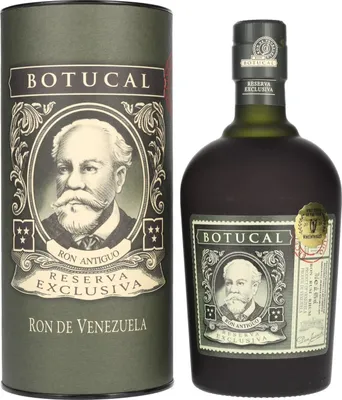 A bottle of Botucal Reserva Exclusiva rum and its cylindrical gift box, both featuring a portrait of a man and ornate designs.