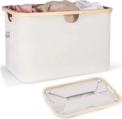 A beige laundry basket with a wooden rim, filled with clothes, and a folded base shown separately.