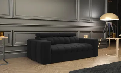 A black sofa is shown in a living room setting with a floor lamp and side tables.