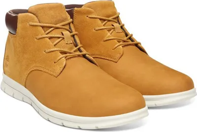 A pair of tan Timberland chukka boots with white soles, shown from a slightly elevated side angle against a white background.
