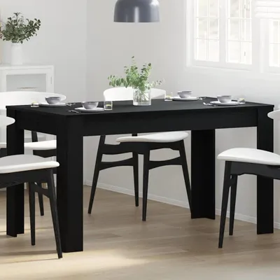 A black dining table with white chairs set for a meal in a dining room.