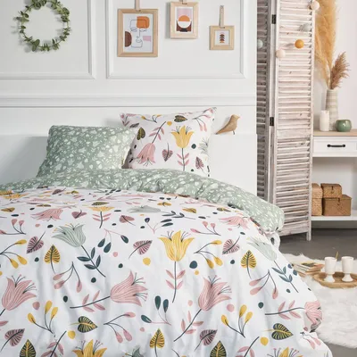 A bedroom scene with a bed made up with floral patterned bedding, pillows, and decorative items.