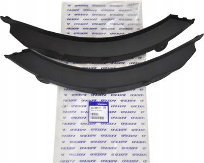 Two black plastic car parts are laid on top of packaging material.