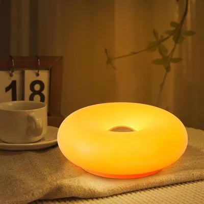 Immagine prodotto di Lampada da tavolo ricaricabile e regolabile, a forma di ciambella. Ideale per la camera da letto, con funzione di ricarica USB, color arancione.
