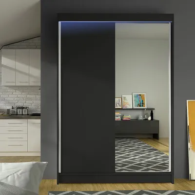 A modern bedroom or living room setting with a wardrobe and kitchen elements in the background.