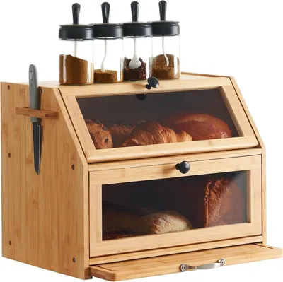 A wooden bread box with glass windows, containing bread and pastries, and topped with spice jars.