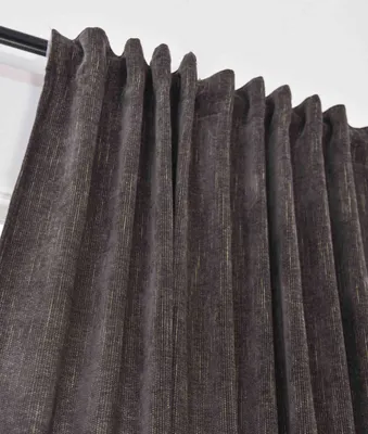 A close-up view of a dark brown curtain with subtle gold threads, hanging from a curtain rod.