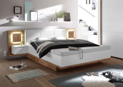 A modern bedroom with a large bed, nightstands, and shelves.