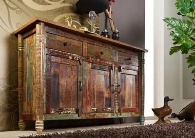 A rustic wooden sideboard with multiple drawers and cabinets, decorated with various items on top and flanking duck figurines.