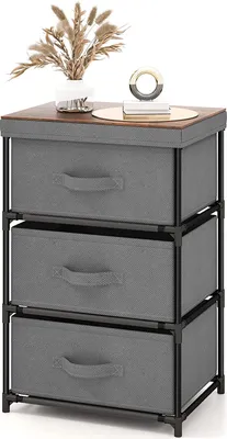 A three-drawer fabric dresser with a wooden top, decorated with a vase of dried flowers and a decorative object.
