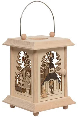 Eine kunstvoll gestaltete Tischlaterne aus Holz zeigt filigrane Schnitzereien mit winterlichen Motiven und einer Kirche im Zentrum während ein Metallgriff oben angebracht ist um die Laterne leicht zu tragen