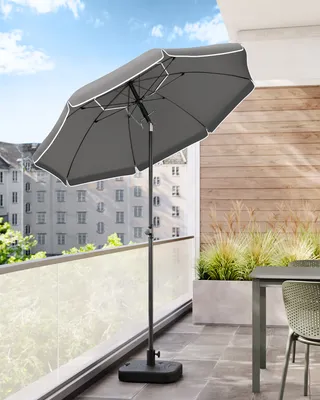 A patio umbrella on a balcony with a table and chairs.