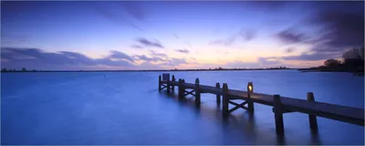 Produktbild von Wallario Poster - Steg bei Abenddämmerung - Blauer Himmel bei Nacht, Kunstdruck Größe: 50 x 125 cm