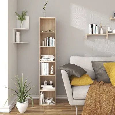 A tall, narrow bookshelf filled with books and decorative items stands next to a sofa in a living room setting.