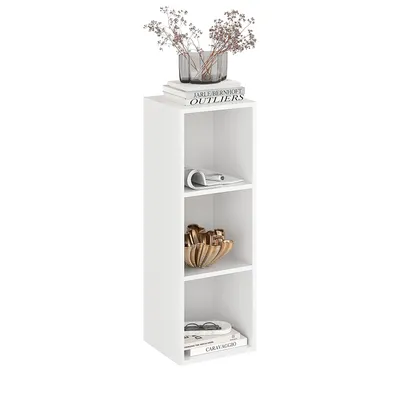 A white, narrow, three-shelf bookcase with decorative items on each shelf and on top.