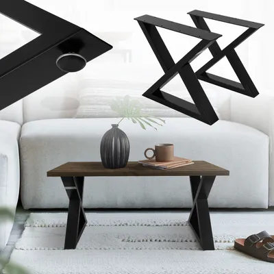 A coffee table with black X-shaped legs, a vase, and a mug on top, placed in a living room setting.