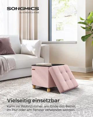 A pastel pink storage ottoman is placed on a textured rug in a living room setting, next to a white sofa.