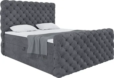 A dark gray upholstered boxspring bed with a headboard and footboard, shown from a diagonal angle against a white background. It includes a mattress and topper, and a grey throw blanket is draped over the foot of the bed.