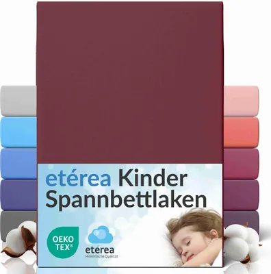 A product image showcasing a burgundy fitted sheet with multiple other colored fitted sheets stacked behind it, along with cotton bolls and a sleeping child.