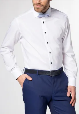 A man wearing a white dress shirt and blue pants, with a light blue bow tie.