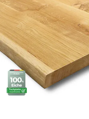 A close-up, angled view of a wooden tabletop with a live edge, set against a white background. A small badge with German flag colors and text is in the lower-left corner.