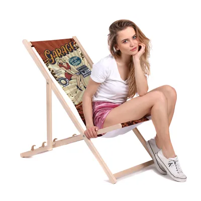 A woman sitting on a folding deck chair with a vintage garage-themed print.