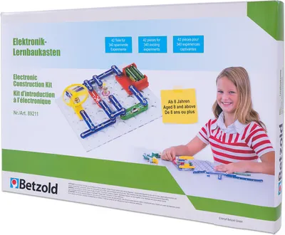 The image shows the packaging of an electronic construction kit, with a young girl interacting with the kit's components.