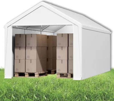 A white storage tent filled with cardboard boxes on pallets, set on a grassy area.