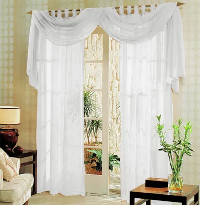 A set of white voile curtains draped over a doorway, with a glimpse of plants and a stone wall visible through the doorway.