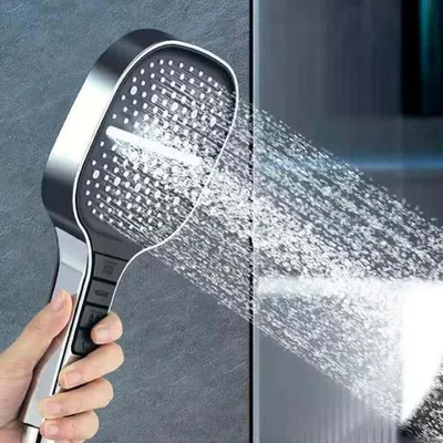 Silberner und schwarzer Handbrausekopf, der Wasser sprüht, von einer Hand gehalten