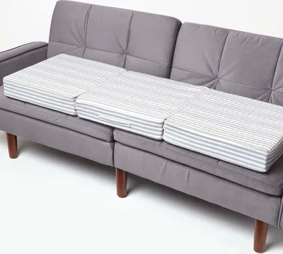 Three striped seat cushions are placed on a gray sofa.