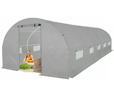 A woman is inside a gray greenhouse, tending to plants.