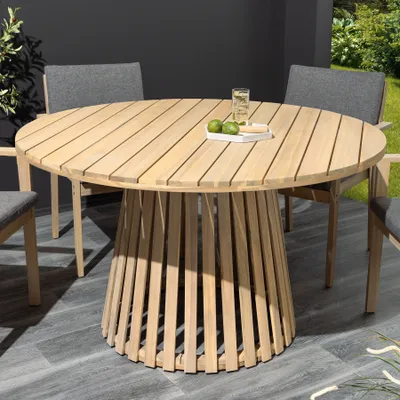 A round wooden garden table with chairs on a patio.