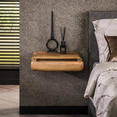 A wooden nightstand with decorative items next to a bed.