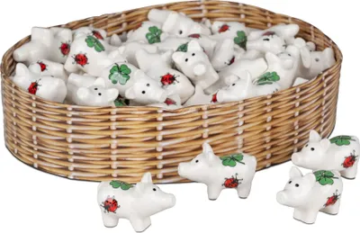 A basket filled with small ceramic pig figurines, some of which are also placed in front of the basket.