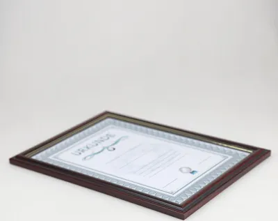 A framed certificate or document is placed on a white surface.