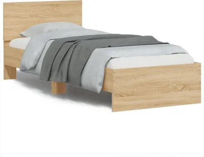 A single bed frame with a headboard, covered with bedding and a blanket.