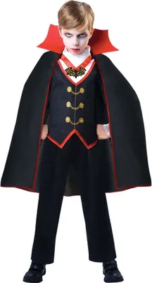 A young boy dressed in a Dracula costume, standing against a white background.