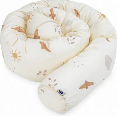 A coiled baby bed guard with a pattern of suns, birds, and leaves.