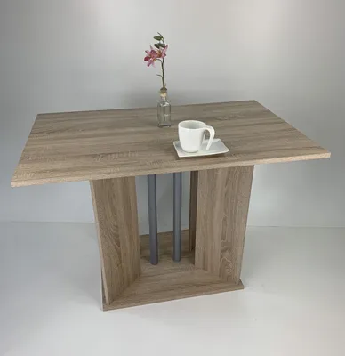 A table with a flower and a cup on it, set against a plain background.