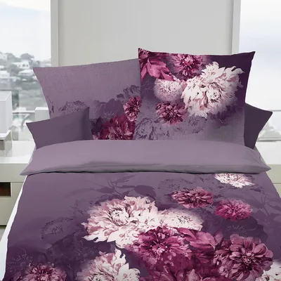 A neatly made bed with purple floral bedding.