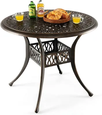 A round outdoor table with decorative elements and a basket of croissants and drinks on top.
