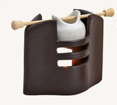 Eine Duftlampe die aus einem dunklen, keramischen Gehäuse mit geschwungener Form besteht.